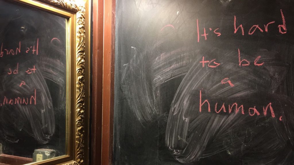 The words It's Hard to Be a Human written on a chalk board.